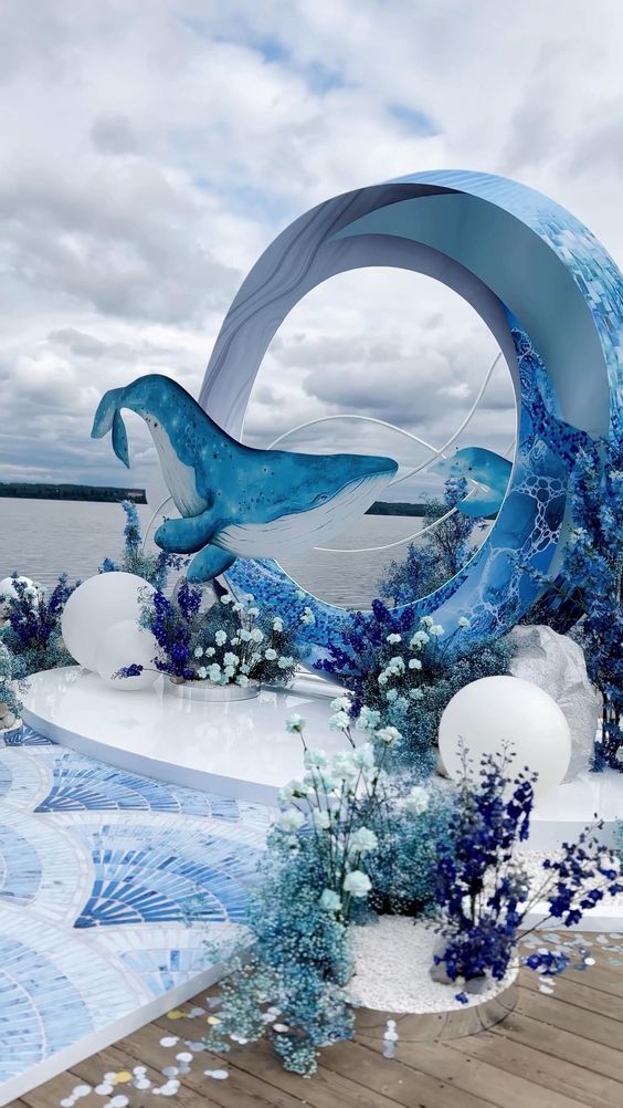 a blue and white sculpture sitting on top of a wooden floor next to the ocean