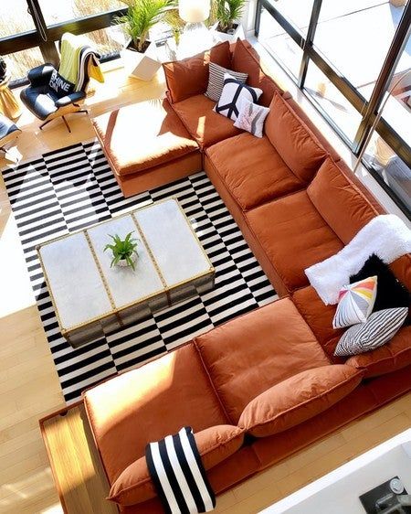 an overhead view of a living room with orange couches and black and white rugs