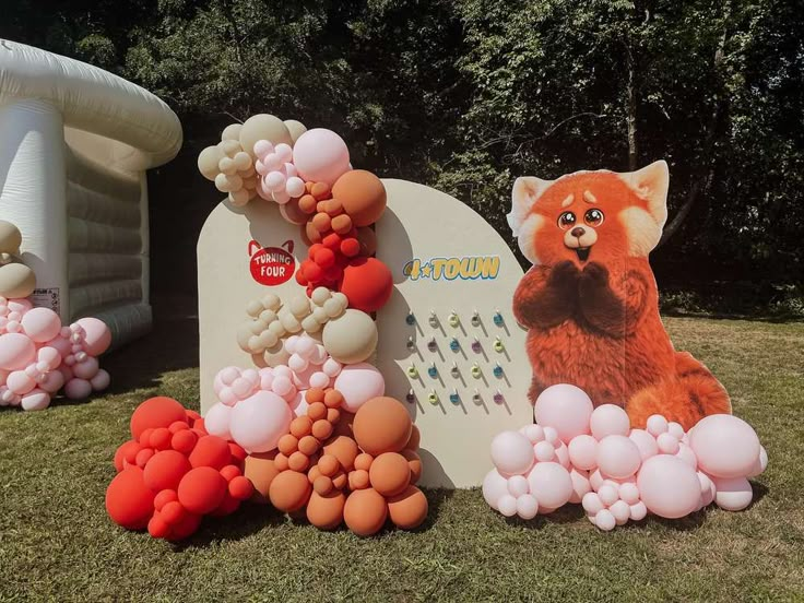 an inflatable sign with balloons and animals on it next to some fake trees