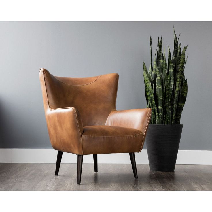 a brown leather chair next to a potted plant