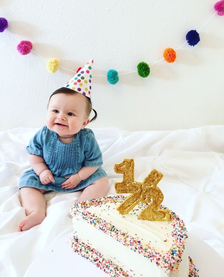 a baby sitting next to a birthday cake