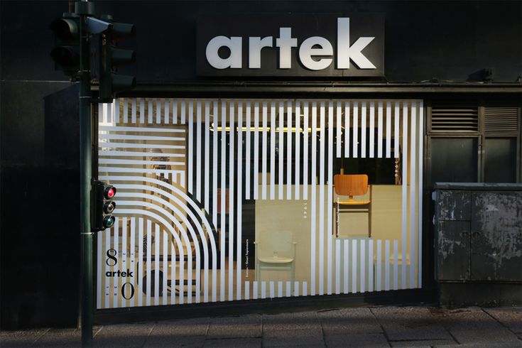 an artek store front with white and black stripes on the glass door, next to a traffic light