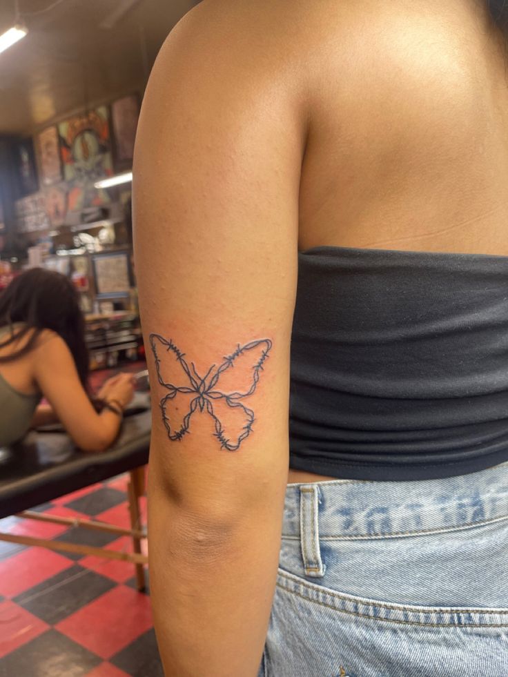 a woman with a butterfly tattoo on her arm in a store aisle next to other women