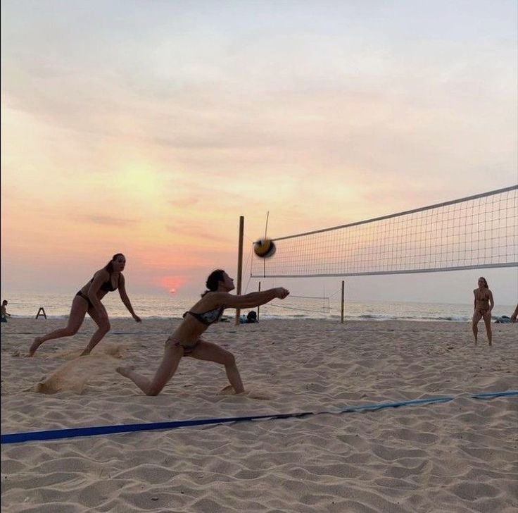 women playing volleyball on the beach at sunset