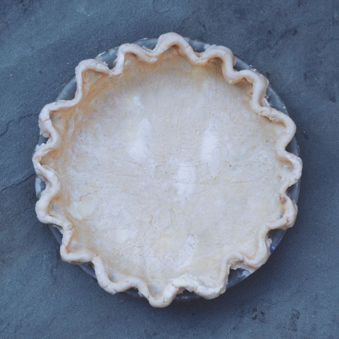 an uncooked pie crust sitting on top of a blue tablecloth covered surface