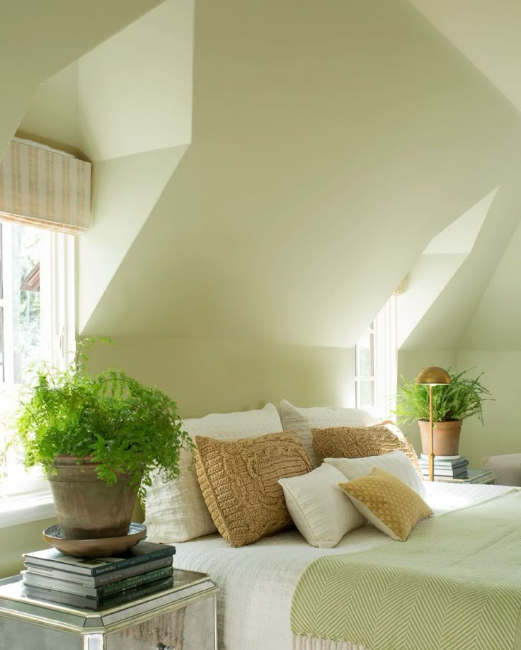 a bedroom with white walls and green plants in the corner on top of the bed