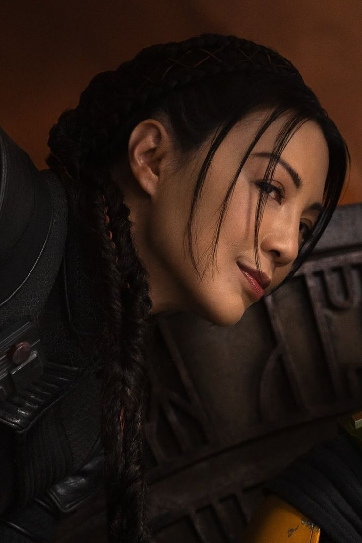 a close up of a person with braids on her head and an orange object