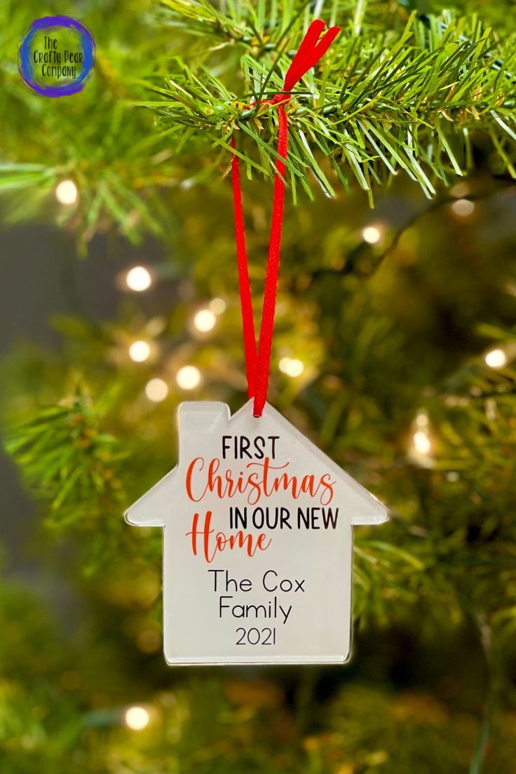 a christmas ornament hanging from a tree with the words first christmas in our new home