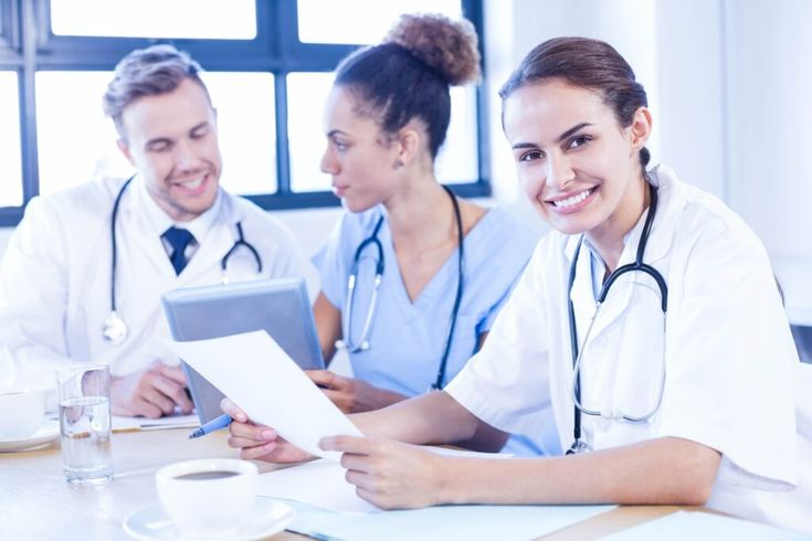 three doctors sitting at a table with papers