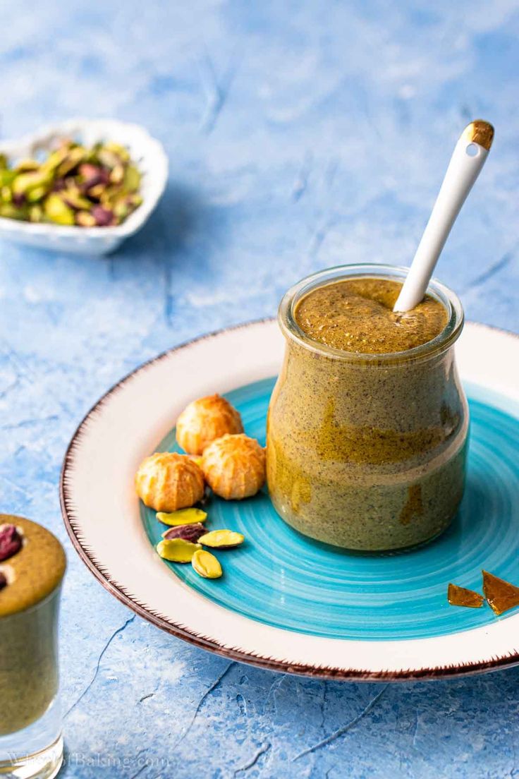 a glass jar filled with food sitting on top of a blue plate next to a cup