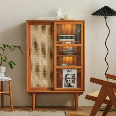 a wooden cabinet sitting next to a table with a potted plant on top of it