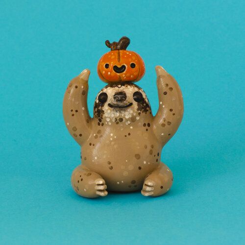 a toy slotty with a pumpkin on its head is sitting in front of a blue background