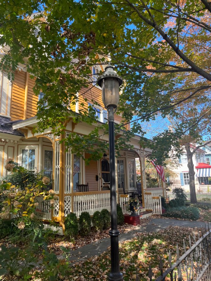 a street light sitting in front of a house on a tree lined sidewalk next to a fence