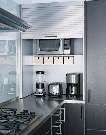 a kitchen with stainless steel counter tops and appliances on the wall, along with open cabinets