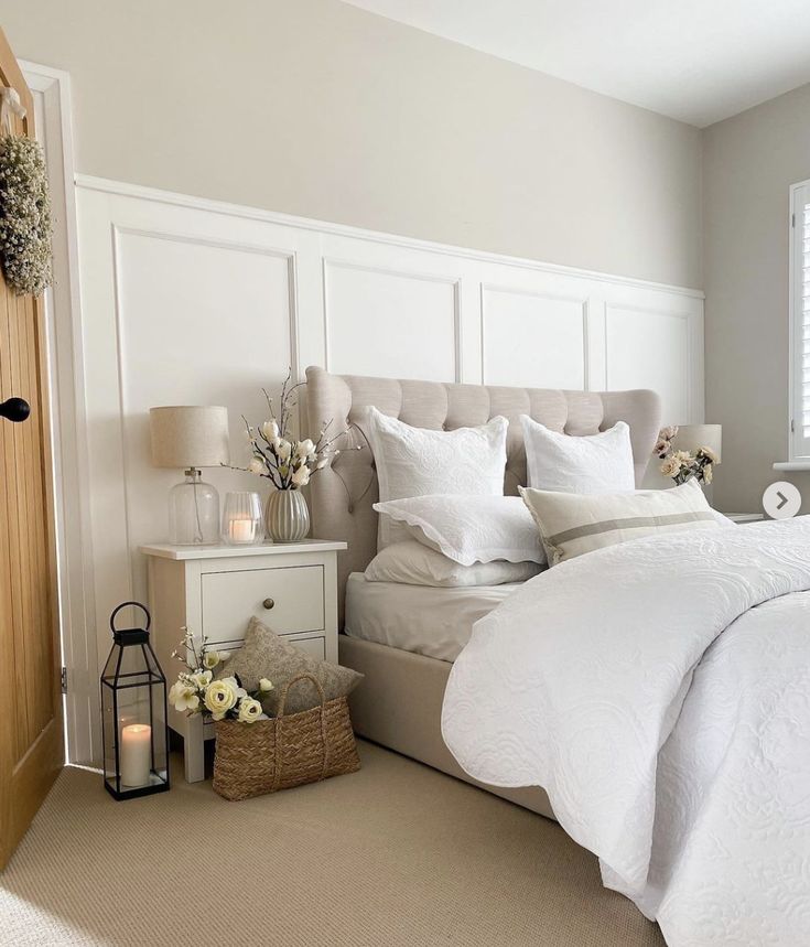 a bed with white linens and pillows in a bedroom next to a wooden door