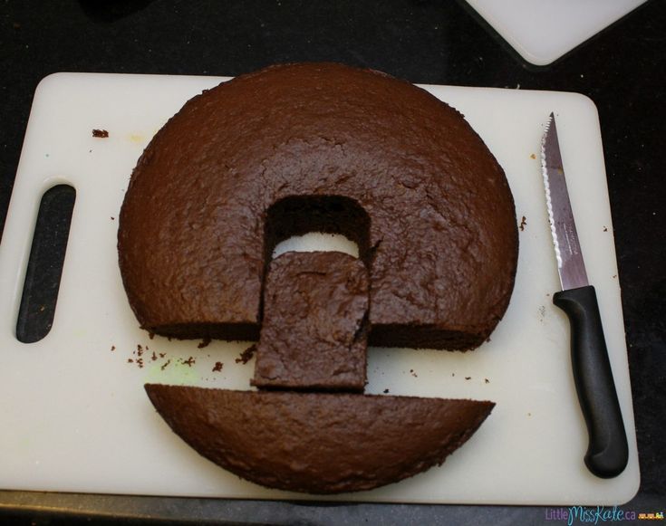 a chocolate cake with the letter e cut in half on a cutting board next to a knife