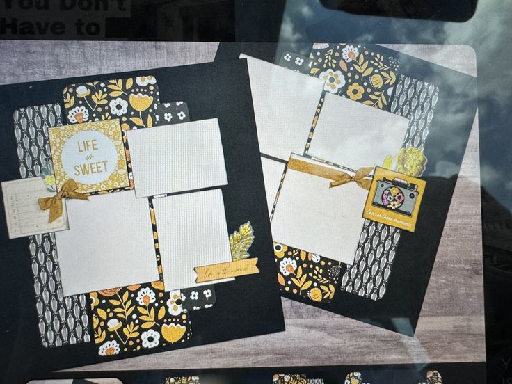 two scrapbook pages with yellow and black designs on them are displayed in a window