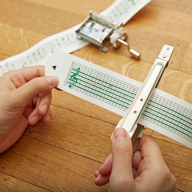 two hands holding a pair of scissors on top of a wooden table next to measuring tape