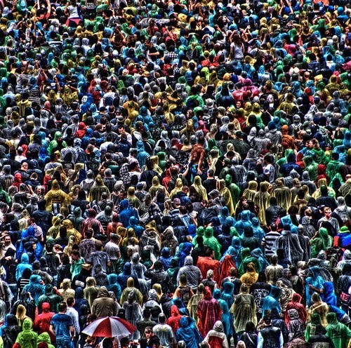 a large group of people standing in the middle of a crowd, all dressed in different colors