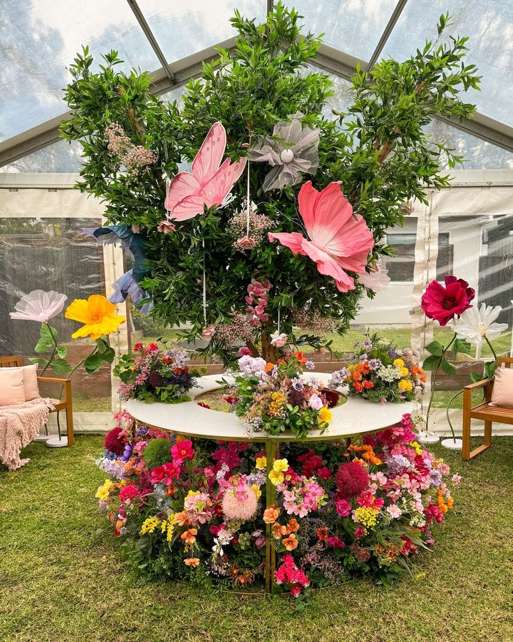 an arrangement of flowers on display in a tent at a flower show with chairs around it