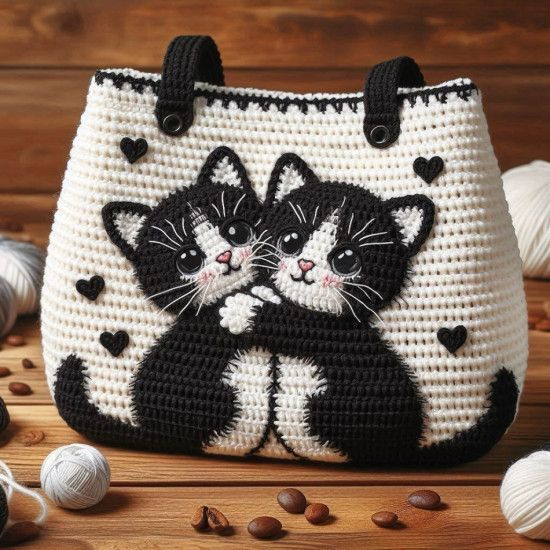 a crocheted bag with two cats on it and balls of yarn in the background