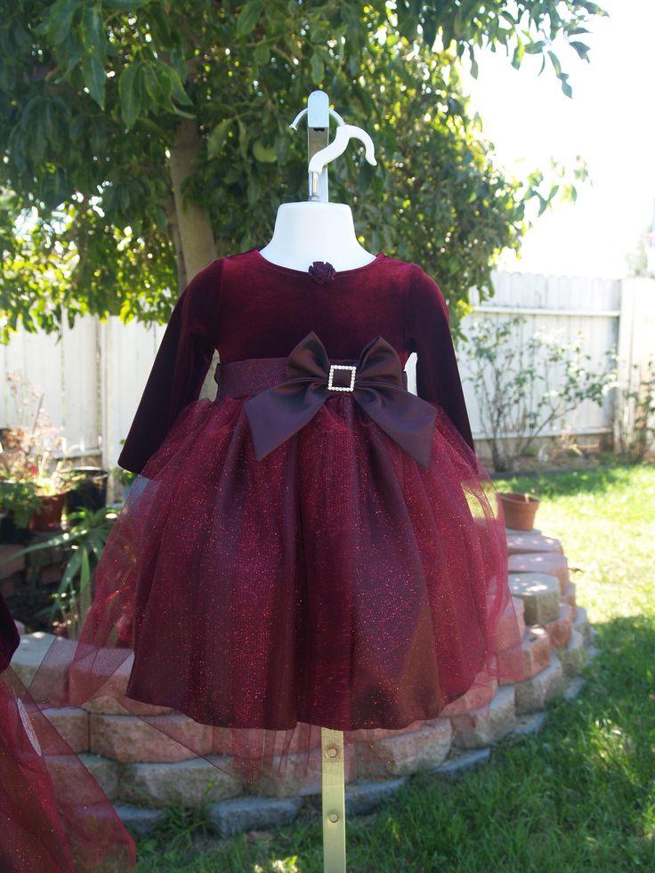 "This is a beautiful, New, Upcycled dress. New dress with Tags! Pictures do not do any justice to this gorgeous dress. This dress comes in a beautiful shade of Burgundy, also available in True Red. The top is Velvet and has a very pretty handmade fabric flower on the round neckline, has long sleeves, and a beautiful taffeta bow with a rhinestone buckle. The top of the skirt is a gorgeous glitter tulle with some hints of red. Dress has a built in crinoline. Please see all pictures!! FOR RED: www. Elegant Tulle Holiday Dress For Festive Occasions, Holiday Tulle Fitted Dress, Fitted Tulle Holiday Dress For Pageants, Fitted Tulle Holiday Dress For Pageant, Fitted Tulle Dress For Holidays, Holiday Tulle Princess Dress, Holiday Princess Dress In Tulle, Elegant Christmas Tutu Dress For Holiday, Elegant Holiday Princess Dress In Tulle