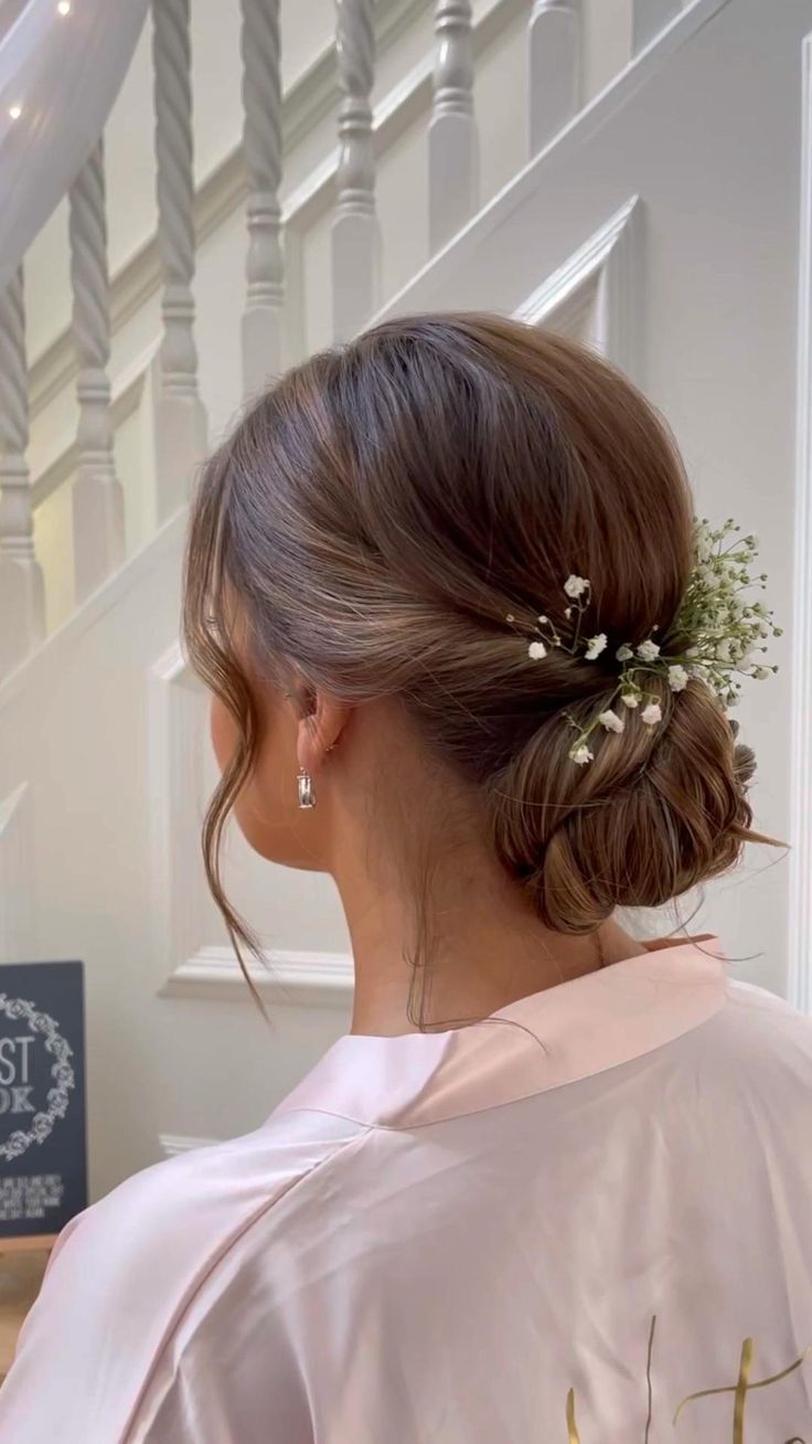 a woman with her hair in a low bun and flowers pinned to her head is looking down at the stairs