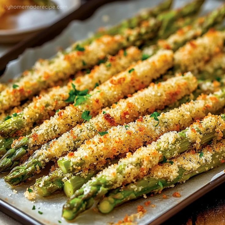 cooked asparagus with parmesan cheese and seasoning on a baking sheet