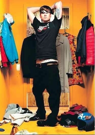 a man standing in front of a closet with clothes on the floor and jacket hanging up