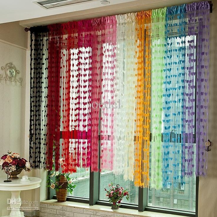 the curtains in this room are colored with different colors and patterns, while the window is decorated with flowers