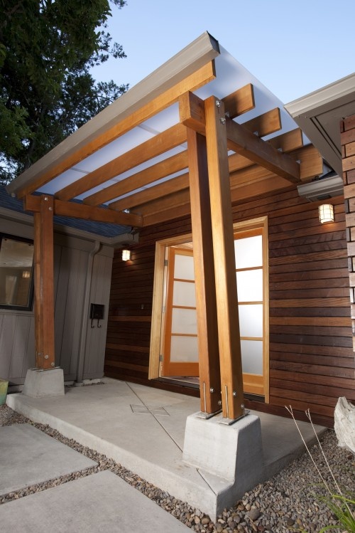 a house with wood siding and a wooden pergolan on the front porch area