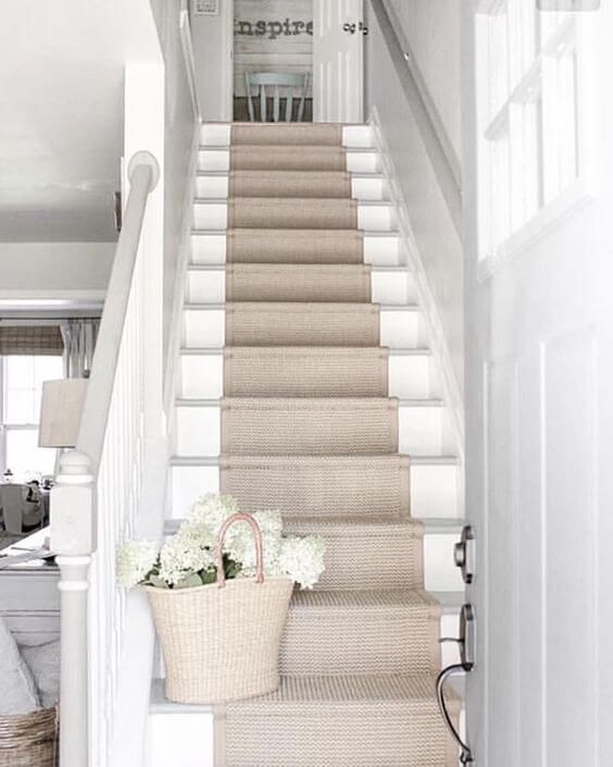 there is a basket with flowers sitting on the stair case next to the carpeted stairs