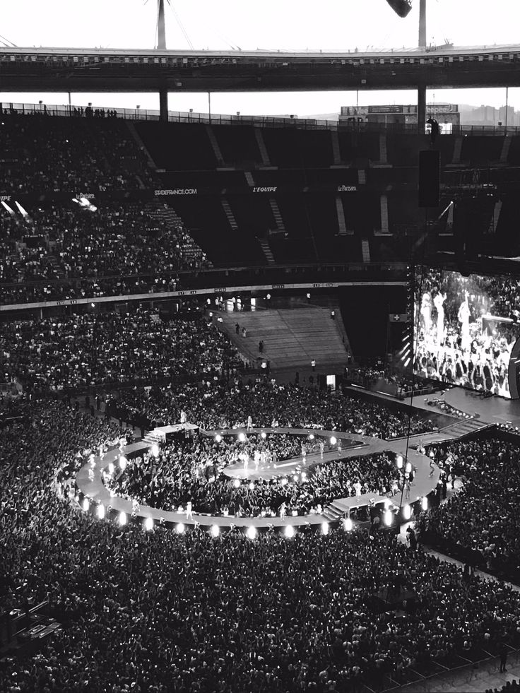 an aerial view of a stadium with many people in the stands and one person standing on a stage