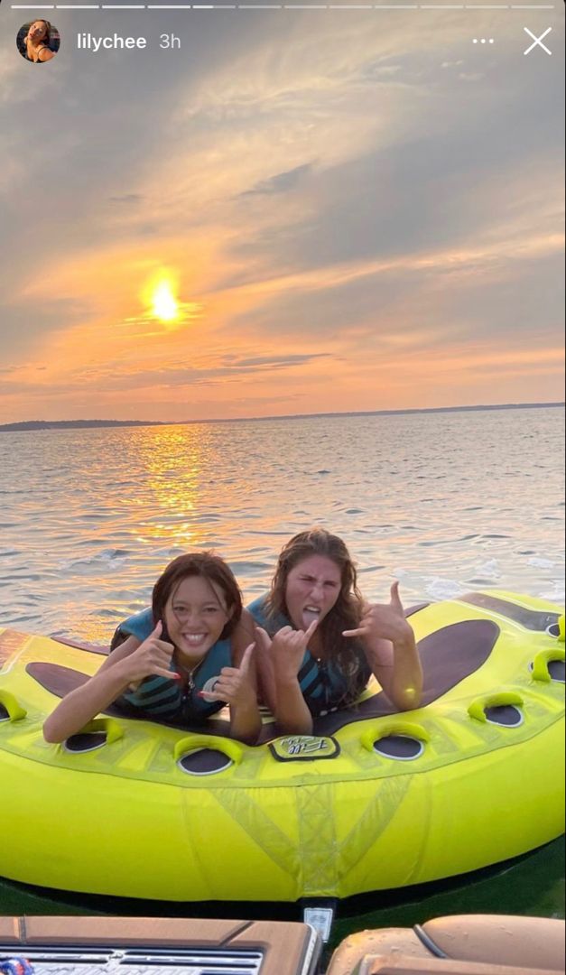 two girls are riding in an inflatable raft on the water at sunset or dawn