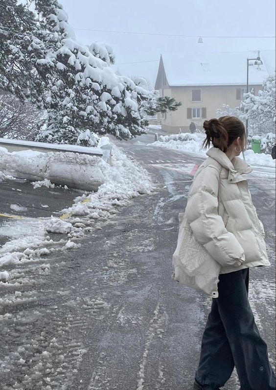 a woman is walking down the street in the snow