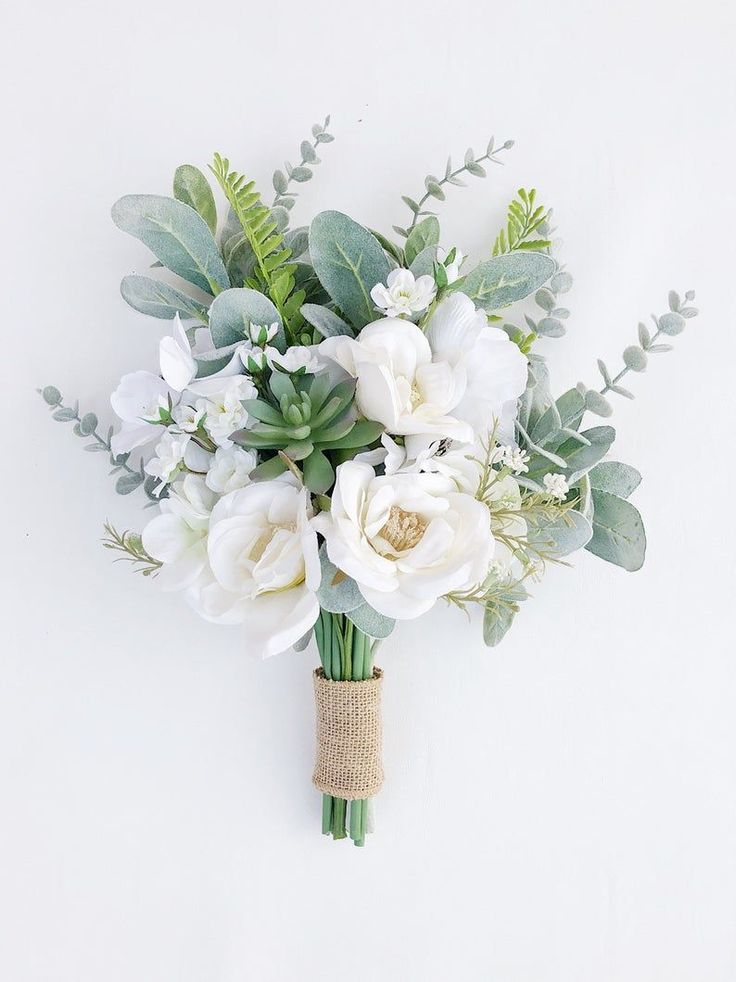 a bouquet of white flowers and greenery on a white background with a burlock