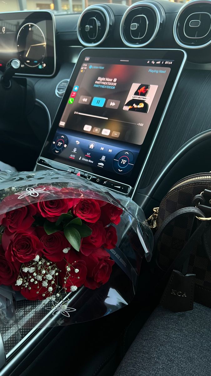 a bouquet of roses is placed in the center console of a car, next to an electronic device