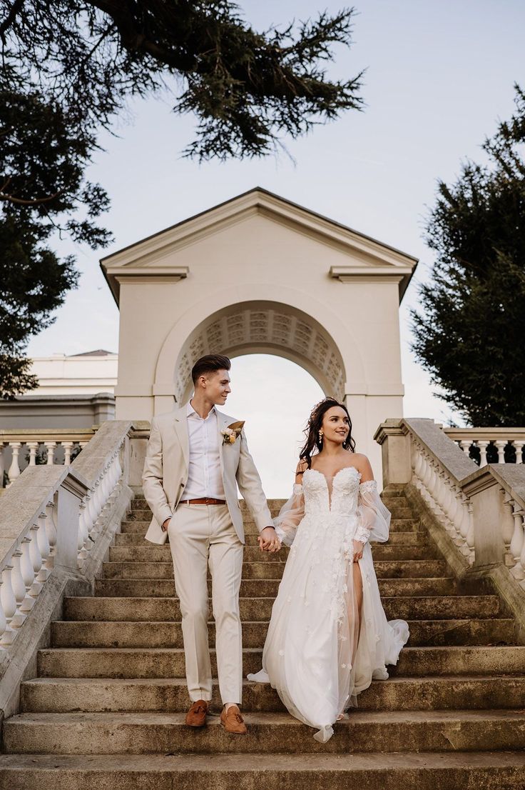 Bride in a strapless princess wedding dress holding hands with her groom in a stone coloured suit in the gardens at Gunnersbury Park Brides Maids And Groomsmen Colour, Light Colour Wedding Suit, Groom And Bride Color Combination, Gunnersbury Park Wedding, Stone Suit Wedding, Stone Wedding Suit, Light Groom Suit, Neutral Groom Suit, Wedding Orangery