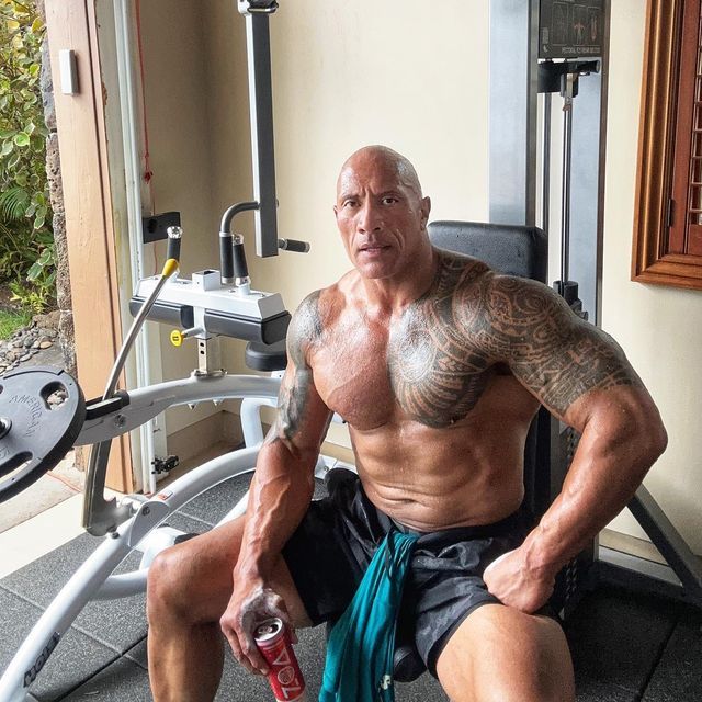 a man sitting on the ground in front of a gym machine with no shirt on