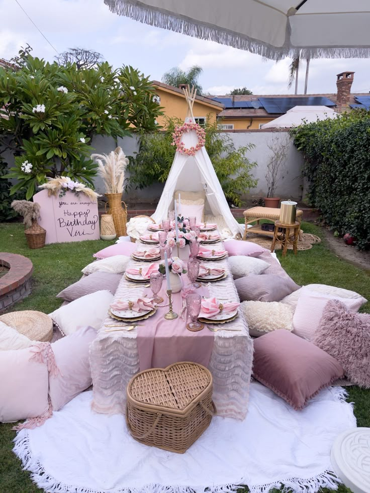 a table is set up with pink and white plates, napkins, and pillows