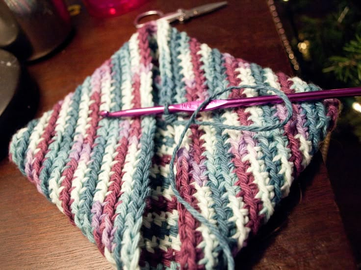 a crocheted dishcloth with a pair of scissors on it next to a christmas tree