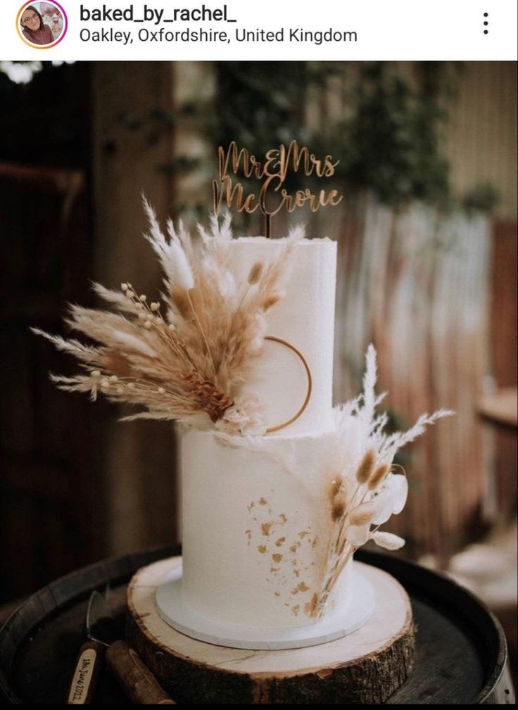 there is a wedding cake on top of a wooden stand with some feathers in it