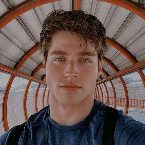 a young man is posing for a photo in front of a metal structure with his eyes wide open