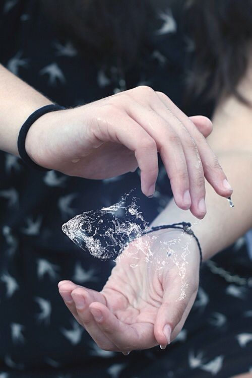 a woman holding something in her hands with water splashing all over her arm and wrist