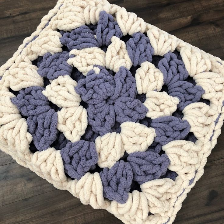 a crocheted square on a wooden surface