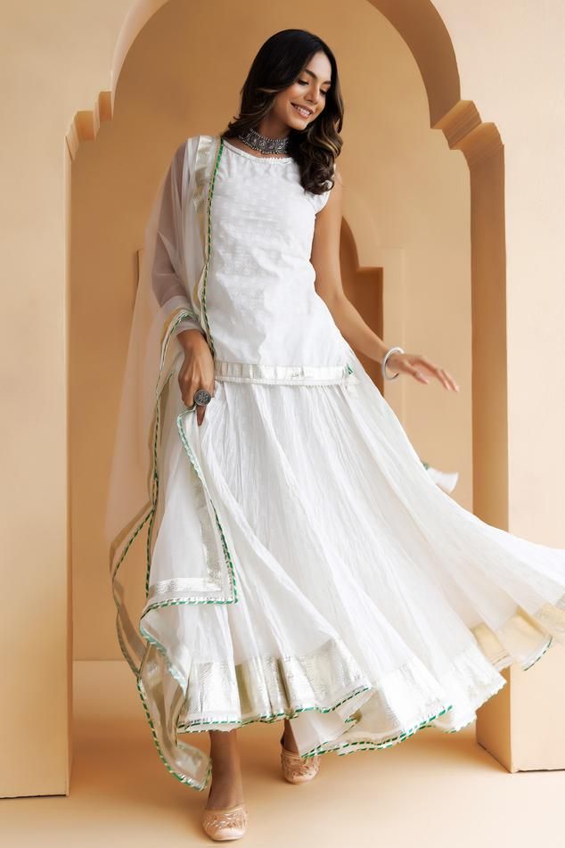 White skirt with gota lappa, magzi embellished borders. Paired with embroidered short kurta and dupatta.
Components: 3
Pattern: Embellished
Type Of Work: Gota lappa, magzi
Neckline: Round
Sleeve Type: Sleeveless
Fabric: Kurta and Skirt: Cotton, Dupatta: Organza
Color: White
Other Details: 
Border embroidered dupatta
Length:
Kurta: 25 inches
Skirt: 36 inches
Dupatta: 2.25 mtrs
Approx. product weight: 300 gms
Disclaimer: Since these products are handcrafted and hand dyed, hence may have slight irr White Dori Work Palazzo Set For Festivals, White Palazzo Set With Dori Work For Festivals, White Chanderi Choli For Transitional Season, Bohemian White Palazzo Set For Wedding, White Chanderi Dress With Gota Work, Bohemian White Palazzo Set With Traditional Drape, White Anarkali Style Sleeveless Sharara, White Sleeveless Anarkali Sharara, White Sleeveless Palazzo Set For Festive Occasions