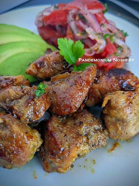 some meat and vegetables on a plate with a small bowl of salsa in the background