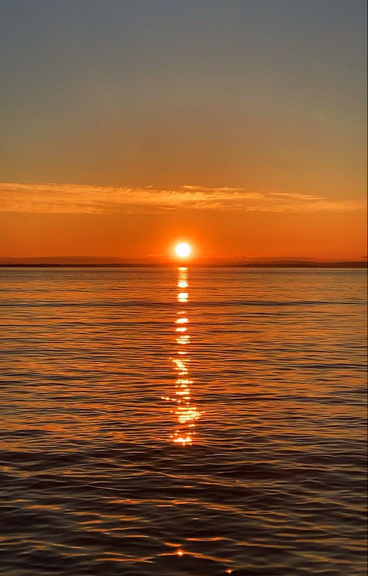 the sun is setting over the ocean with calm water