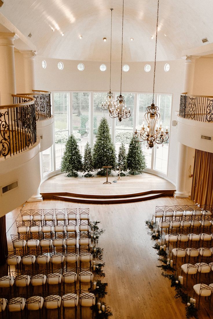 an indoor wedding venue with chandeliers and chairs set up for a ceremony in front of large windows