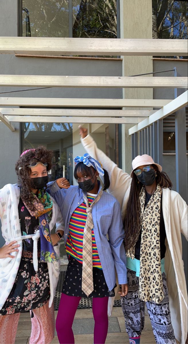 three people wearing face masks and standing in front of a building with their arms up